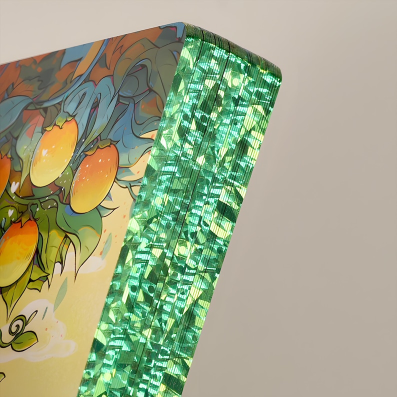 May include: A stack of art prints with a vibrant illustration of orange fruit on a tree. The edges of the prints have a shimmering green effect, creating a unique visual texture. The artwork features a colorful, detailed design.