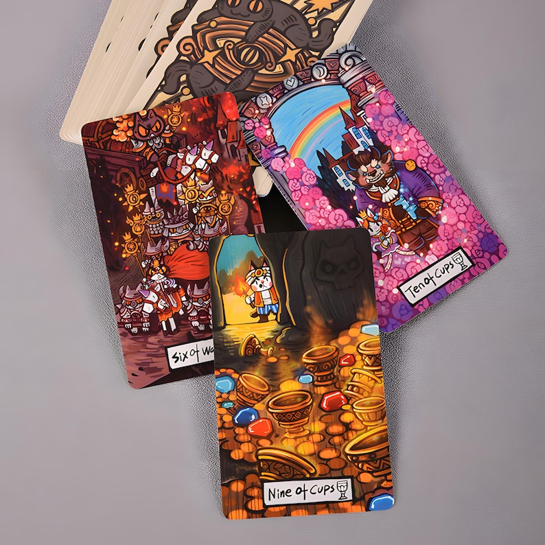 May include: A collection of tarot cards featuring colorful illustrations. The cards display fantasy-themed artwork with characters and symbols. The "Nine of Cups" card shows a character in a cave with treasure. The "Ten of Cups" card shows a character in front of a castle.
