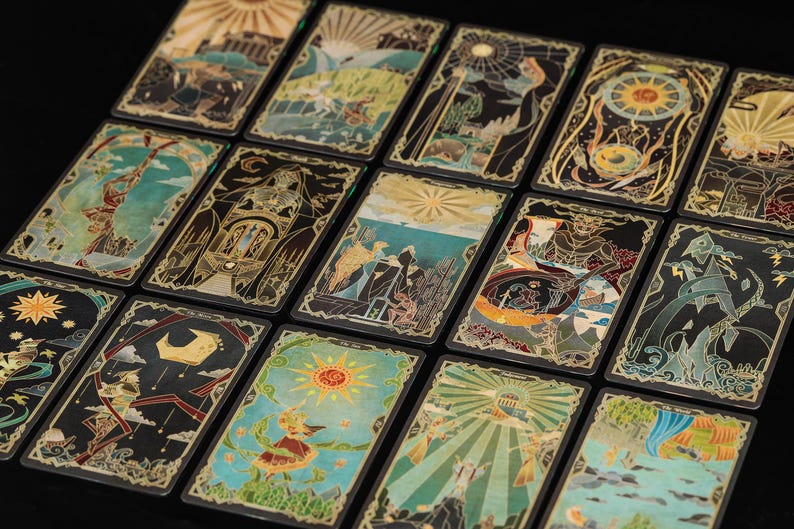May include: A collection of rectangular tarot cards arranged in a grid, each featuring intricate, colourful illustrations with gold-toned line work. The designs depict various symbolic scenes, celestial bodies, and figures against dark backgrounds.