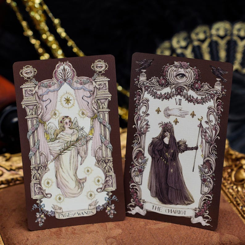 May include: Two rectangular tarot cards with dark brown borders. The left card, labeled Page of Wands, depicts an angel figure in a white robe. The right card, labeled The Chariot, shows a cloaked figure holding a staff beneath an eye symbol.