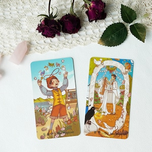 May include: Two tarot cards, one depicting a magician with a wand and a top hat, and the other depicting a couple getting married under a floral archway. The magician card is labeled "The Magician" and the wedding card is labeled "The World".