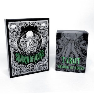 May include: A black tarot card box and deck featuring a detailed illustration of a creature with tentacles, skulls, and the text "SHADOW OF AEONS" and "TAROT". The design is in shades of gray and green.