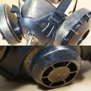 May include: A steampunk-style gas mask with a brass finish and a gear detail. The mask has a black strap and a black and brass filter.