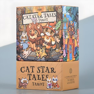May include: Two stacked tarot card boxes. The top box features a colorful illustration of cat characters with the text "CAT STAR TALES TAROT." The bottom box is tan with the same text and cat illustrations. The box reads "78 CARDS WITH BOOK."