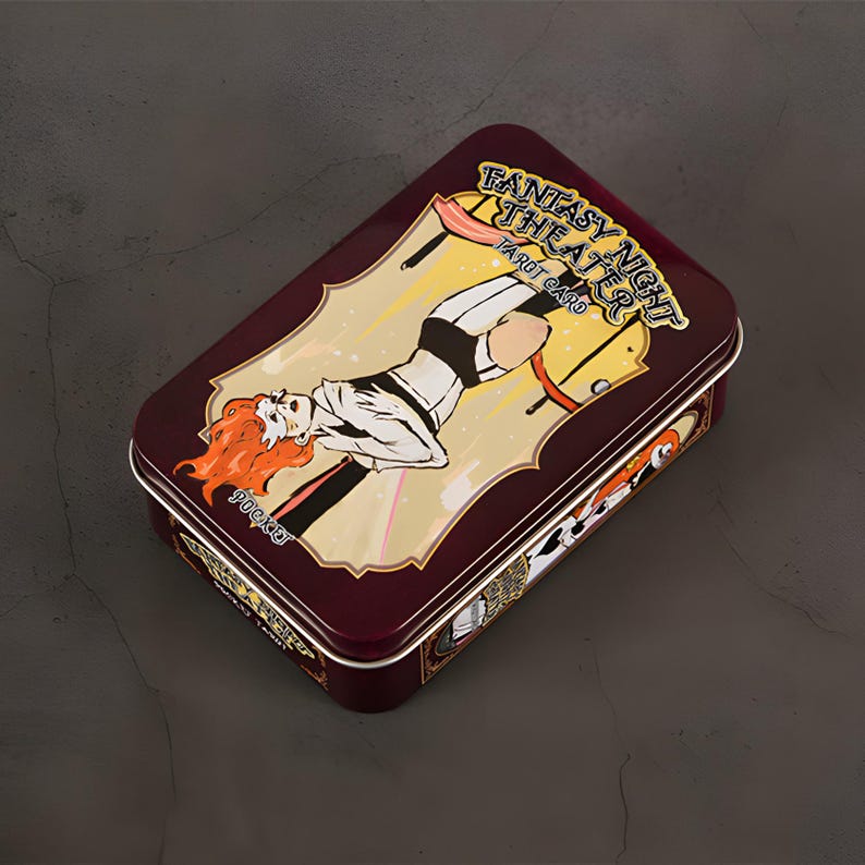 May include: A rectangular, maroon metal tin with a decorative illustration. The illustration features a woman with red hair in a black and white outfit, with the text "FANTASY NIGHT THEATER TAROT CARD" and "POCKET".