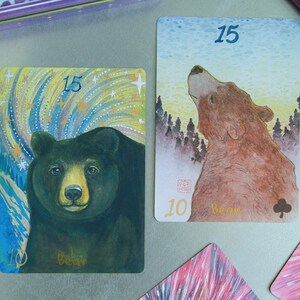 May include: Two rectangular playing cards featuring bear illustrations. The left card shows a black bear against a starry sky with the number 15 and the word bear. The right card shows a brown bear looking upward at a forest with the number 15.