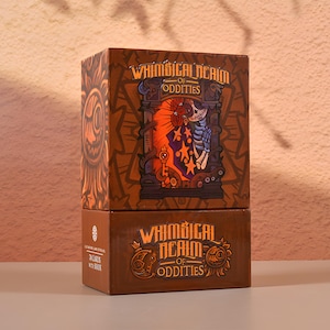 May include: Two-piece brown box set with the text "Whimsical Realm of Oddities". The top box features a colorful illustration of a skeleton and other imagery. The bottom box has the text "78 cards with book".
