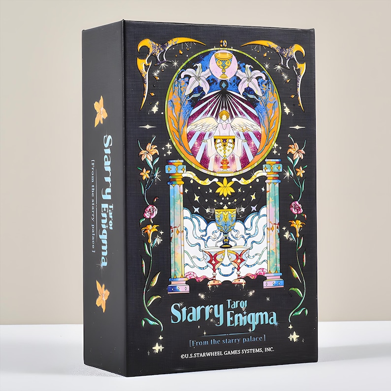 May include: A black tarot card box with the title "Starry Enigma" in white and blue. The box features a colorful illustration of a chalice, angel, and floral elements. The text "From the starry palace" is also visible.