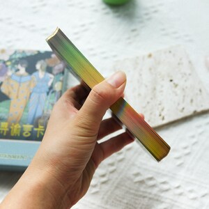 May include: A deck of tarot cards with a rainbow iridescent foil finish on the spine. The cards are in a blue box with the text "Early  Morning Tarot" in Chinese characters.