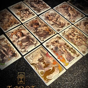 May include: A set of tarot cards with intricate, vintage-style illustrations. The cards depict angels, cups, and other symbolic imagery. The text "TAROT THE FOREST KNOWS" is visible at the bottom of the image, with card titles like "Two of Cups".