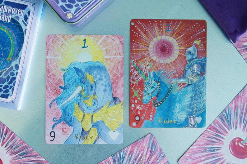 May include: Two rectangular tarot cards featuring illustrations of a blue unicorn and a knight on horseback. The left card shows a blue unicorn with a yellow mane and the number 9, while the right card depicts a knight on a blue horse with the text Rider.
