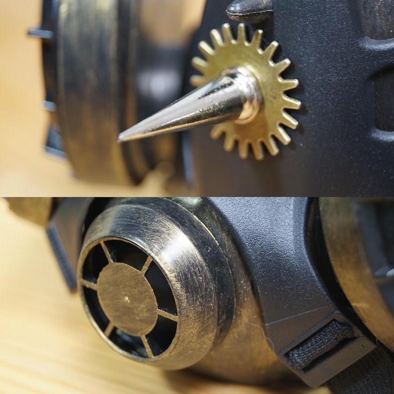 May include: A steampunk-style gas mask with a gold and black finish. The mask has a large, round, gear-shaped detail on the side, a pointed metal spike, and a small, round, metal vent on the front.