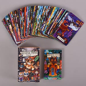 May include: A deck of Cat Star Tales Tarot cards fanned out, with two boxes below. The cards feature colorful illustrations of cats in various scenes. The boxes display the title "Cat Star Tales Tarot" with cat-themed artwork.