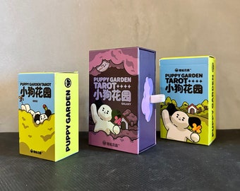 May include: Three colorful boxes with illustrations of cartoon dogs and flowers. The boxes are labeled "Puppy Garden Tarot" and feature the text "小狗花园" in Chinese characters. The boxes are a purple, blue, and yellow color.