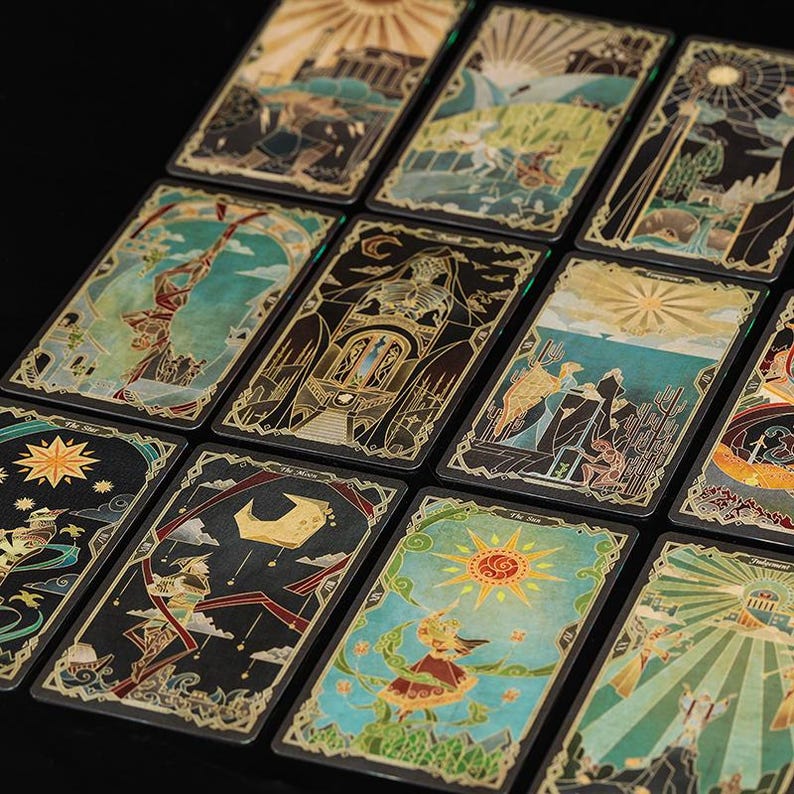 May include: A collection of rectangular tarot cards arranged in a grid, featuring intricate illustrations with gold-toned line work on dark backgrounds. Each card displays unique symbolic imagery, including celestial bodies, figures, and architectural elements.