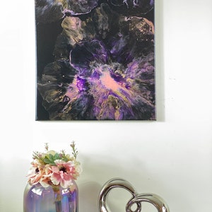 May include: Abstract painting on canvas with purple, pink, gold, and black colors. The painting features a swirling, fluid design that resembles flowers.