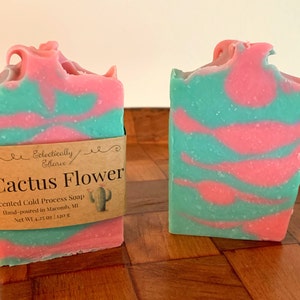 May include: Two bars of handmade soap with a pink and green swirl design. The soap is labeled "Cactus Flower" and is scented with a cold process. The soap is hand-poured in Macomb, MI and weighs 4.25 oz or 120 g.