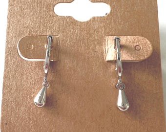 May include: A pair of silver-colored teardrop earrings displayed on a brown earring card. The earrings have a simple, elegant design with a small, rounded top and a teardrop-shaped pendant. The card has a slot for hanging.
