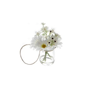 May include: A small glass vase with a white string handle, filled with white flowers. The vase is hanging from the string.