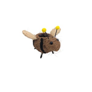 May include: A novelty bee-shaped planter crafted from brown natural fibres. The bee features black stripes, beige wings, and yellow antennae. This planter is designed for small plants or flowers, bringing a natural element to any setting.
