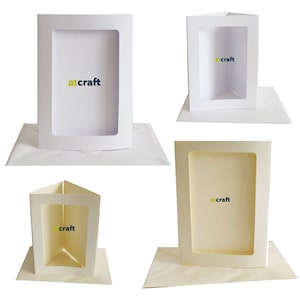 May include: Four white and cream card bases with a window cut out. The cards are folded in half and have a white envelope. The cards have the text "a1craft" printed on them.