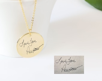 Puede incluir: Collar de oro con un colgante redondo que presenta un mensaje escrito a mano que dice "Love you Pawpaw".