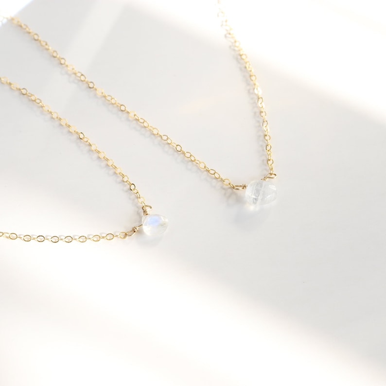 Puede incluir: Dos delicados collares de oro con colgantes de piedra lunar. Los collares est&aacute;n superpuestos, con el collar m&aacute;s corto que presenta un colgante de piedra lunar m&aacute;s peque&ntilde;o.