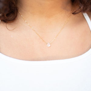 Puede incluir: Un delicado collar de cadena de oro con un peque&ntilde;o colgante de piedra preciosa transparente. El collar mide 40,6 cm de largo y est&aacute; hecho de oro. El colgante es peque&ntilde;o y redondo, y est&aacute; engastado en un engaste de oro. El collar es una pieza de joyer&iacute;a simple y elegante que ser&iacute;a un gran regalo para cualquier ocasi&oacute;n.
