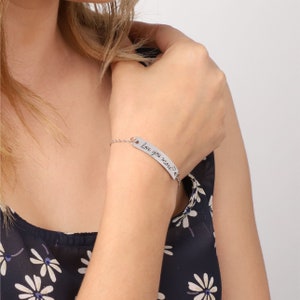 Puede incluir: Pulsera de plata con una cadena fina y un dije rectangular que dice "Love you more" con un s&iacute;mbolo de coraz&oacute;n.