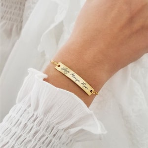 Puede incluir: Pulsera de cadena dorada con un dije rectangular de barra grabado con el mensaje escrito a mano "Love Always, Mom".