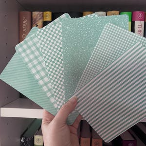 May include: A set of rectangular cards featuring various sage green patterns including stripes, checkered squares, gingham, and speckled textures. The cards are arranged in a fan shape, displaying a consistent color palette of light green and white.