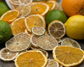 May include: Dried orange and lime slices arranged on a wooden surface. The slices are a mix of yellow, orange, and green colours.