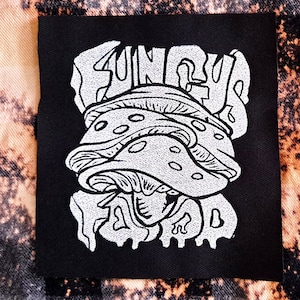 May include: Black embroidered patch featuring a white mushroom design and the text "FUN GUY FOOD" in a stylised font.