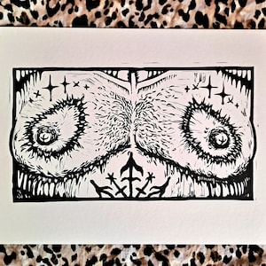 May include: Black and white linocut print of a stylized image of two eyes with a star above each eye and a stylized cross below.