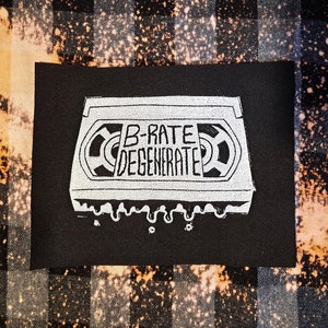May include: Black fabric patch with a white graphic of a cassette tape with the text "B-Rate Degenerate" on it.