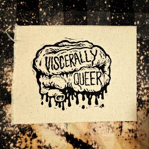 Könnte beinhalten: Ein quadratischer, cremefarbener Stoffaufnäher mit einer schwarzen Illustration eines Gehirns und den Worten "VISCERALLY QUEER". Die Gehirnillustration hat einen tropfenden Effekt am unteren Rand. Der Aufnäher ist vor einem schwarz-weiß karierten Hintergrund platziert.