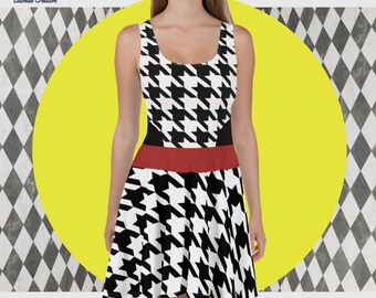 Puede incluir: Un vestido skater de estampado pata de gallo en blanco y negro con una banda roja. El vestido es sin mangas y tiene un escote redondo.