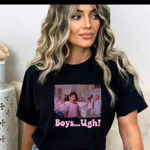 May include: Black t-shirt with a pink graphic of a scene from the movie "Mean Girls". The graphic features a young girl in a pink dress with the text "Boys... Ugh!" underneath.
