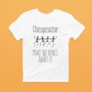 May include: White t-shirt with the word "Chiropractor" above a line of dancing skeleton figures. Below the skeletons, the text reads "MAKE NO BONES ABOUT IT". The shirt is displayed on an orange background.