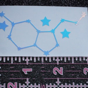 May include: A blue iridescent vinyl sticker of the constellation Gemini. The sticker is on a white background and is approximately 2 inches wide.