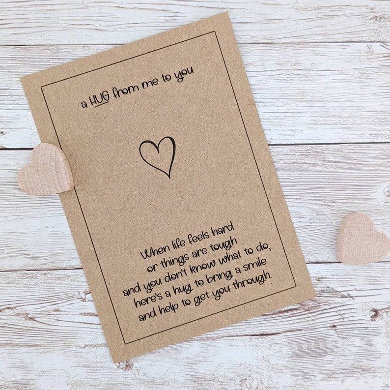 May include: A brown card with a heart drawn on it and the text "a HUG from me to you". The card has a poem about hugs and how they can help when life is tough.