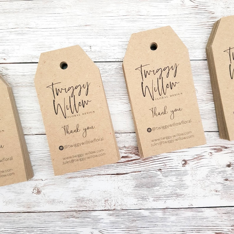 Puede incluir: Una pila de etiquetas de regalo de papel marr&oacute;n con el texto "Twiggy Willow Floral Design" y "Gracias" impreso en ellas. Las etiquetas tambi&eacute;n incluyen el nombre de usuario de las redes sociales "@twiggywillowfloral" y la direcci&oacute;n del sitio web "www.twiggy-willow.com".