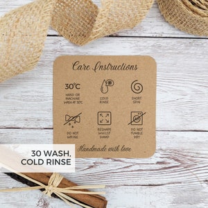 May include: A brown card with care instructions for washing a garment. The card has a 30 degree Celsius symbol, a cold rinse symbol, a short spin symbol, a do not wring symbol, a reshape whilst damp symbol, and a do not tumble dry symbol. The card also says "30 wash, cold rinse" and "Handmade with love".
