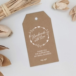 May include: A brown paper tag with a hole at the top. The tag features white text that reads "Handmade with Love" inside a circular design of arrows and hearts. Below, it says "THANK YOU FOR SUPPORTING MY SMALL BUSINESS."