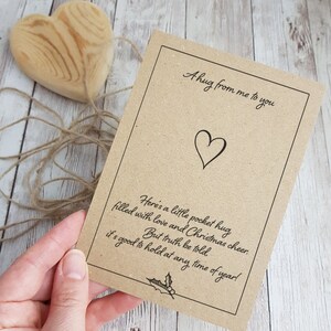 May include: A brown card with a heart and the text "A hug from me to you" and "Here's a little pocket hug filled with love and Christmas cheer. But truth be told, it's good to hold at any time of year!"