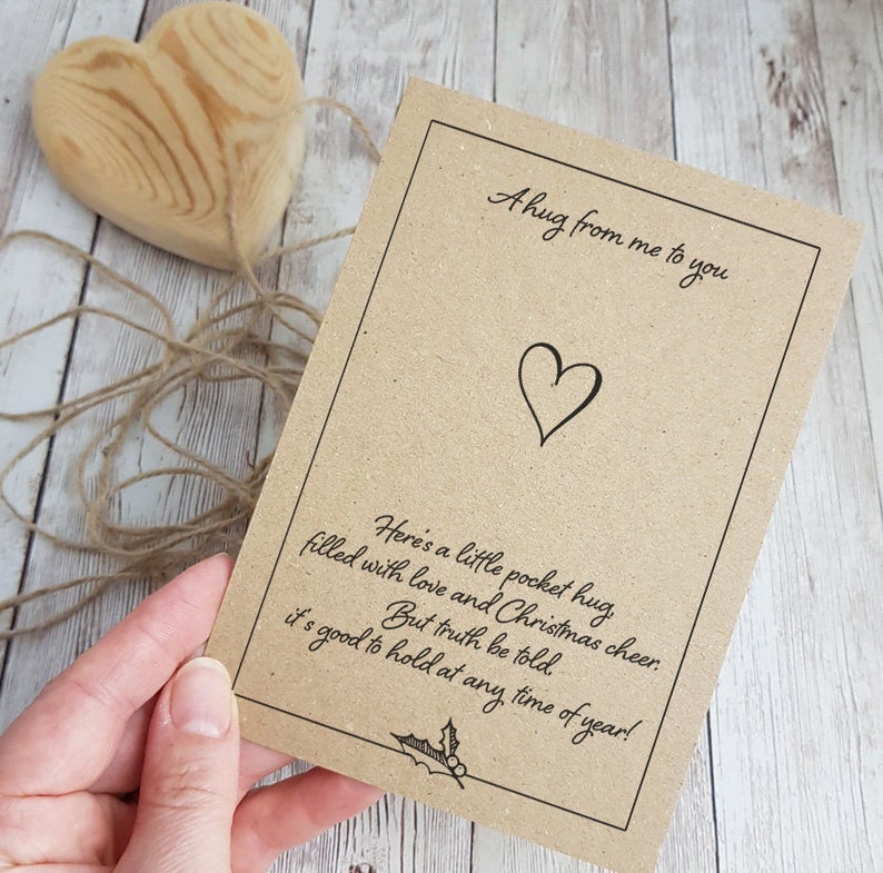 May include: A brown card with a heart and the text "A hug from me to you" and "Here's a little pocket hug filled with love and Christmas cheer. But truth be told, it's good to hold at any time of year!"