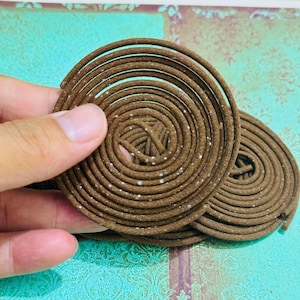 May include: Two brown spiral incense coils with white specks. The coils are stacked on top of each other.
