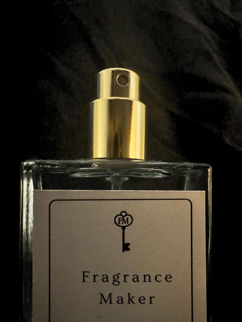 Close-up detail of the premium gold spray nozzle on the FragranceMaker perfume bottle. Highlighting the artisanal glass quality, secure crimping, and signature brand label detail.