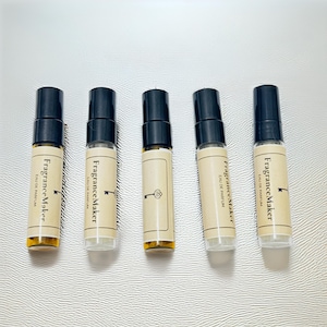 Pode incluir: Cinco frascos de amostra de perfume com tampas pretas e rótulos que dizem "Fragrance Maker EAU DE PARFUM". Os frascos estão cheios de um líquido âmbar claro e estão dispostos em uma fileira.