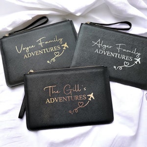 May include: Three black zippered pouches with gold lettering. The pouches are personalized with the text "Voyce Family Adventures", "Alger Family Adventures", and "The Gill's Adventures". Each pouch features a gold airplane and heart design.